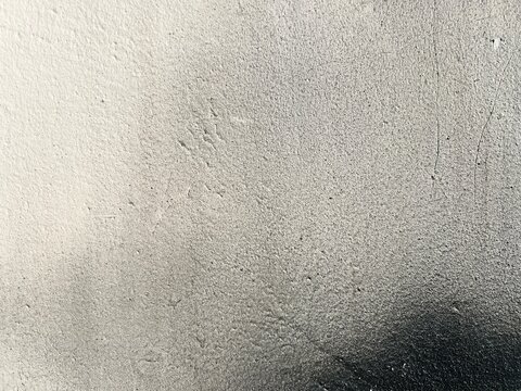 Abstract close-up texture of a concrete surface with spray paint gradient transition from light white to dark gray.