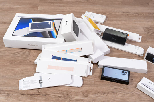 Rostov, Russia - April 04, 2022: A pile of retail Apple products boxes for a laptop, smartphone, tablet, smartwatch and accessories lies scattered on a wooden floor, a concept of unboxing