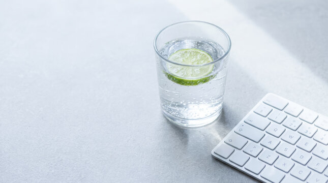 Workation workspace with sparkling water and lime beside white keyboard in soft natural light for remote productivity