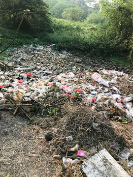 Wide view of mixed garbage covering a vegetated ravine, ideal for waste management, environmental crisis, municipal cleanup, sustainability, and pollution awareness campaigns.