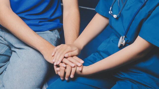 Doctor holding patient's hand on a white desk during medical consultation, offering support, empathy, care, reassurance, and compassion in a hospital or clinic setting