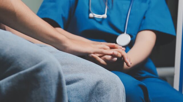 Doctor holding patient's hand on a white desk during medical consultation, offering support, empathy, care, reassurance, and compassion in a hospital or clinic setting