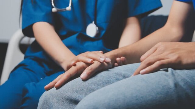 Doctor holding patient's hand on a white desk during medical consultation, offering support, empathy, care, reassurance, and compassion in a hospital or clinic setting