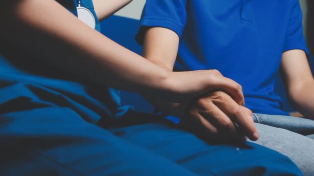 Doctor holding patient's hand on a white desk during medical consultation, offering support, empathy, care, reassurance, and compassion in a hospital or clinic setting