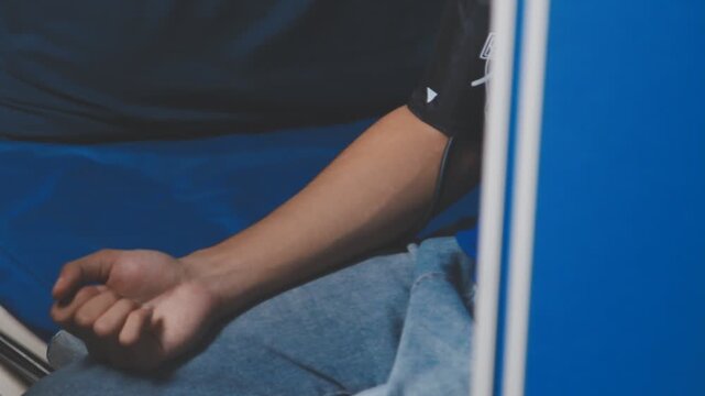 Female healthcare worker taking blood pressure on an adult male patient in a medical clinic, close-up with cropped faces