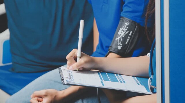 Female healthcare worker taking blood pressure on an adult male patient in a medical clinic, close-up with cropped faces