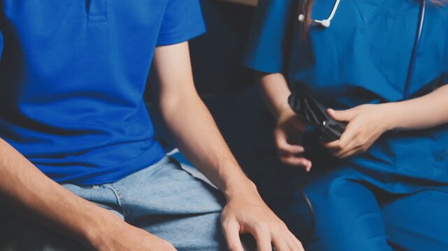 Female healthcare worker taking blood pressure on an adult male patient in a medical clinic, close-up with cropped faces