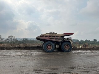 Large dump truck carrying heavy load on dusty haul road at open pit industrial mining location © faaqiihh