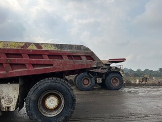 Close up profile view of massive mining dump truck wheels and body on haul road at mine site © faaqiihh