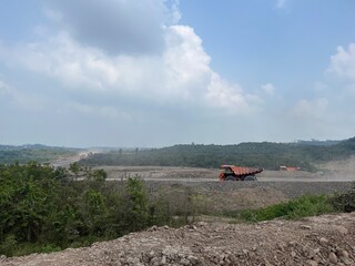 Heavy haul truck driving on a dirty road in an open pit coal mine under bright blue sky © faaqiihh