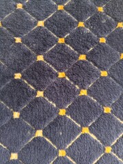 Obraz premium Quilted navy blue fabric texture with yellow diamond pattern for background design.