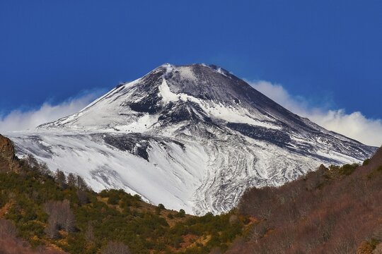 Snow-capped Etna peaks, volcano with snow-capped peak against blue sky, barren vegetation in the foreground, UNESCO World Heritage Site Etna, volcano, volcanism, Sicily, Italy