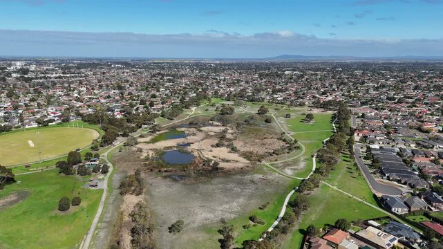 Aerial view of Heathdale Glen Orden Wetlands, surrounded by walking paths, sports field, and suburban residential housing in Werribee, Melbourne, Victoria, Australia. Habitat retention and green space