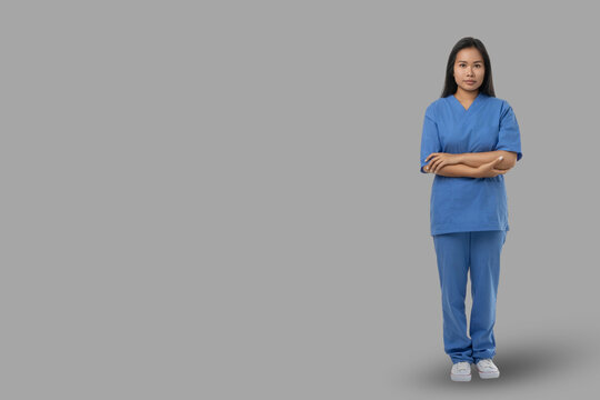 A medical worker poses in scrubs with a neutral expression