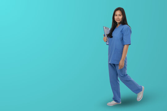 Woman in blue medical outfit holds clipboard in studio space
