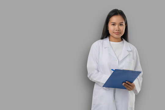 Medical worker stands with clipboard in a studio backdrop