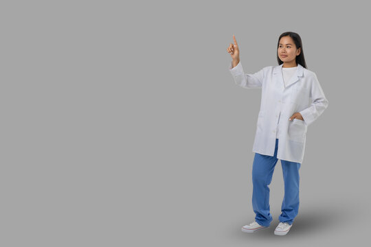 Young female medical worker on gray background, space for text