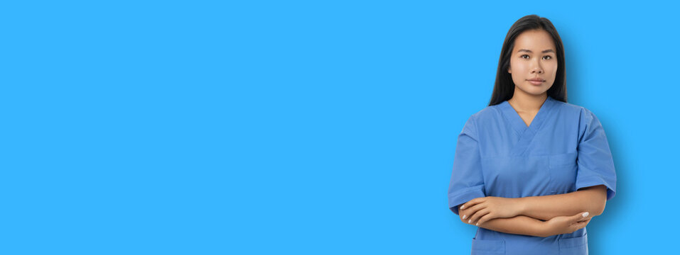 Medical worker poses with crossed arms against a blue backdrop