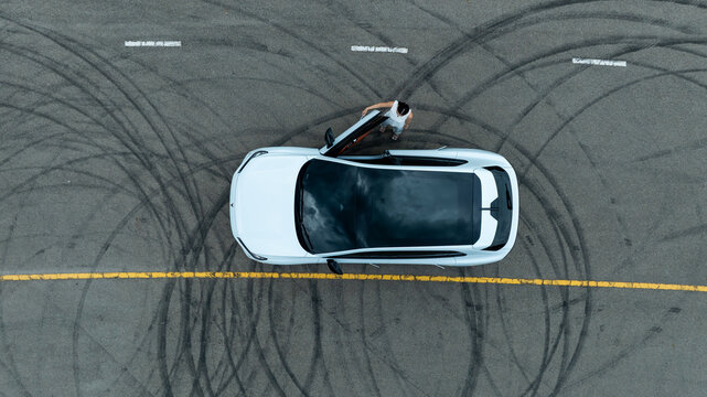 Top view of white ev car.
New ev car on tire marks.
Fast ev car parked on road.