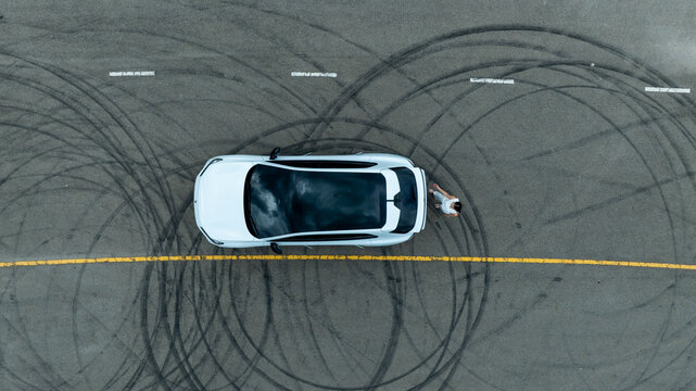 Top view of white ev car.
New ev car on tire marks.
Fast ev car parked on road.