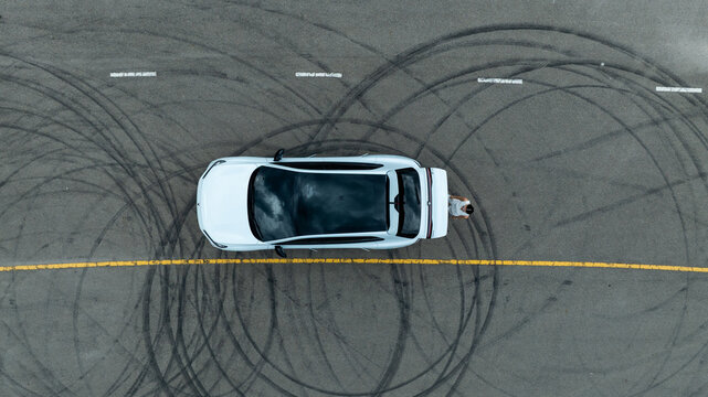 Top view of white ev car.
New ev car on tire marks.
Fast ev car parked on road.