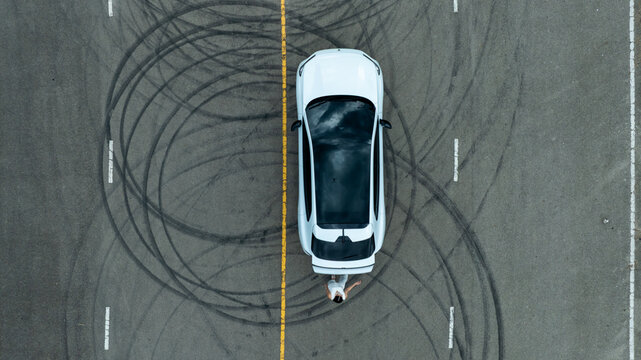 Top view of white ev car.
New ev car on tire marks.
Fast ev car parked on road.