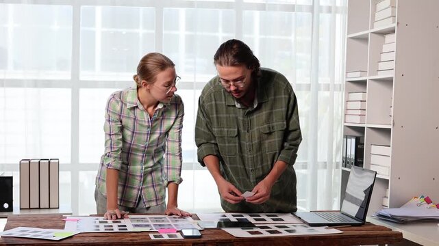 Web designers collaborating on ux/ui interface development, brainstorming app wireframes for mobile phone screens and discussing project strategy in a creative office