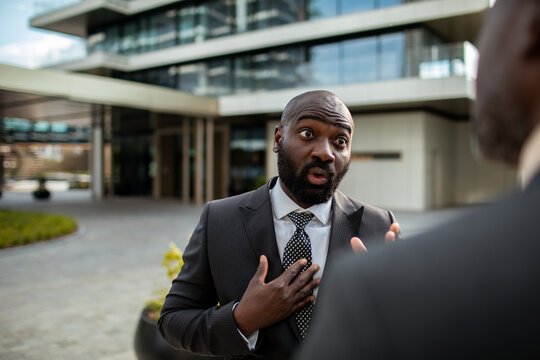 Surprised businessman reacting during conversation outside office building