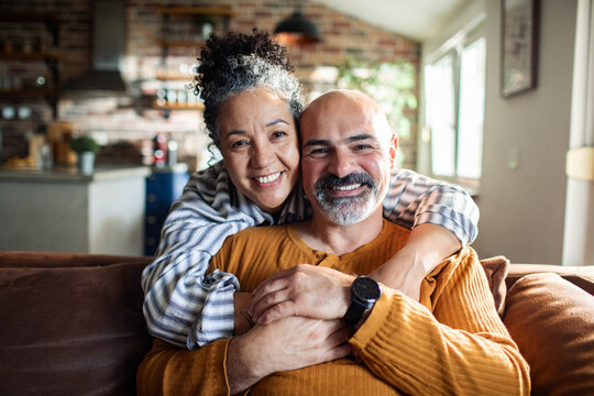 Happy mature couple hugging on couch at home
