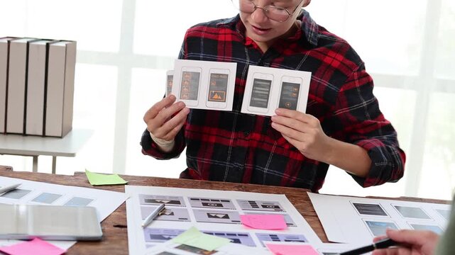 Creative ui designer presenting mobile application prototypes for user experience development during a collaborative ux brainstorming meeting in a modern design agency office