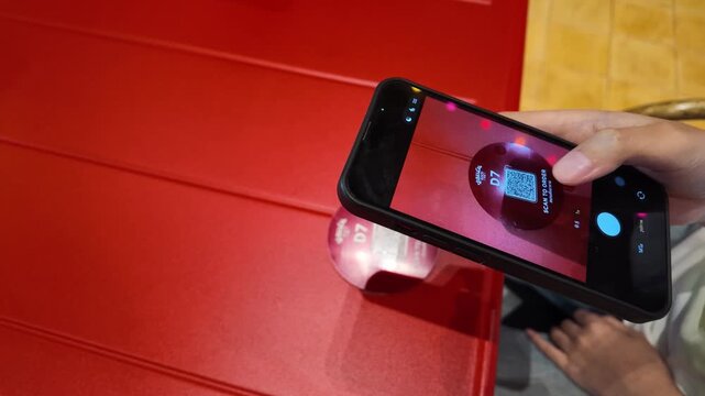 Person Scanning QR Code with Smartphone at Restaurant Table