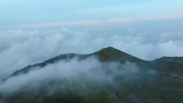 Aerial View of Green Mountain Farmland with Rolling Clouds in Central Java