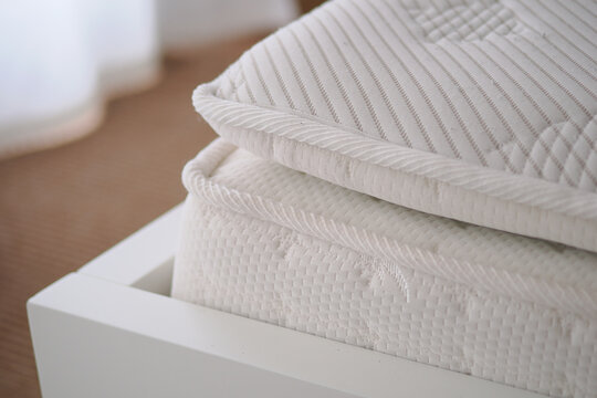 Soft mattress on a bed frame in a bright room