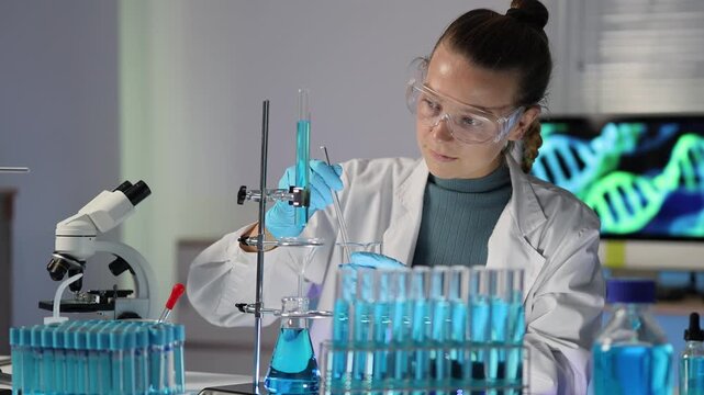 Female biochemist performing genetic research with test tubes and a microscope, conducting chemical experiments in a cutting-edge laboratory with dna helix on screen