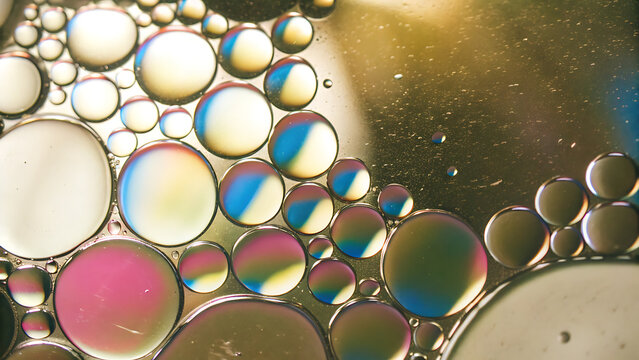 Macro abstract photograph of colorful oil and water bubbles in a liquid mixture.