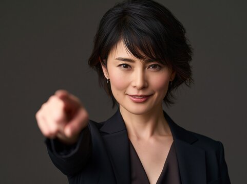 はつらつとした笑顔で人差し指を前に突き出し「あなた」を示す女性