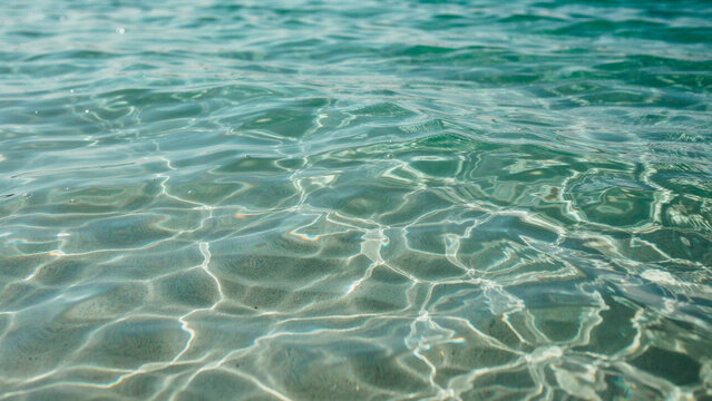 Clear turquoise sea water surface with sunlight reflections and rippling patterns turquoise reflection sunlight transparent tropical
