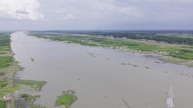 Aerial drone footage shows a wide river winding through green agricultural fields, rural settlements, waterways, and fertile riverine landscape, creating a detailed view of the countryside.