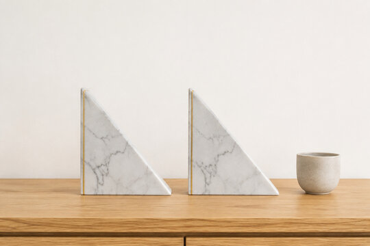 Two identical triangular bookends in row on oak desk with ceramic cup, minimalist desk organization concept