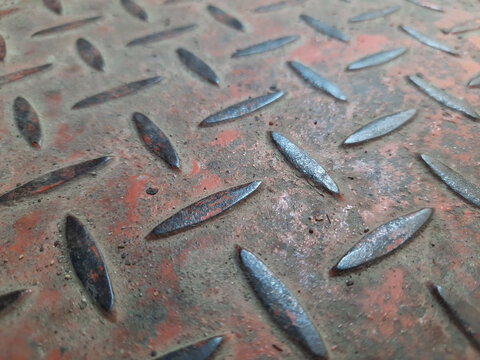 Perspective view of a rusty diamond steel plate with a weathered red surface.
