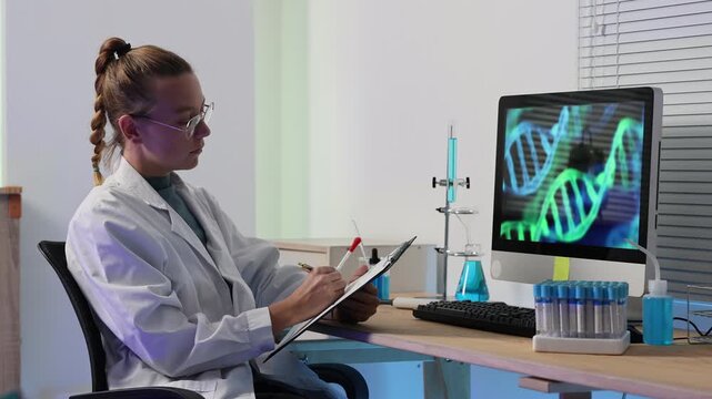 Female geneticist in a modern laboratory analyzing data and handling test tubes while examining dna helix structure on a computer monitor, showcasing scientific innovation