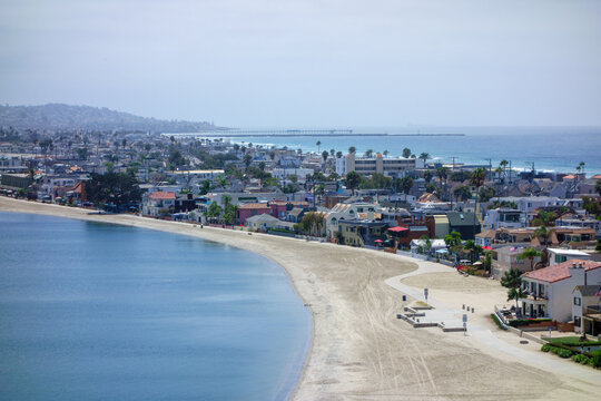 Aerial perspective of the vacation community of Mission Beach, featuring a sandy curved shoreline of Sail Bay and the Pacific ocean coastline, San Diego, CA