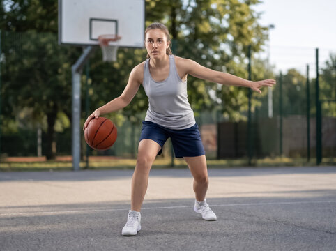 Female basketball player dribbling on outdoor court