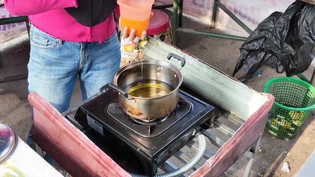Hand coat and dip skewers into hot oil, crafting freshly prepared street food with skillful speed and care.