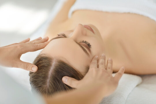 Head massage therapy, relaxing luxury procedure for woman in beauty salon. Hands of professional therapist touch skin, massaging scalp of lying client for relax, stress relief. Spa treatment concept