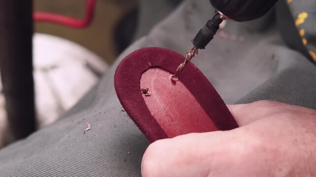 Shoemaker occupation. Handmade craft. Professional cobbler hands using power drill making holes in leather shoe sole in workshop.