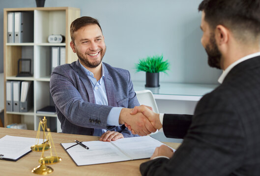 Smiling attorney or lawyer shakes hand with client during office meeting, focusing on law and collaboration in a professional setting with a sense of deal and agreement and positive negotiation.