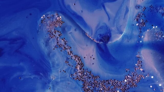 Shiny fluid texture. Shimmering art. Defocused blue color sequin bright particles floating in paint water wave on abstract background.