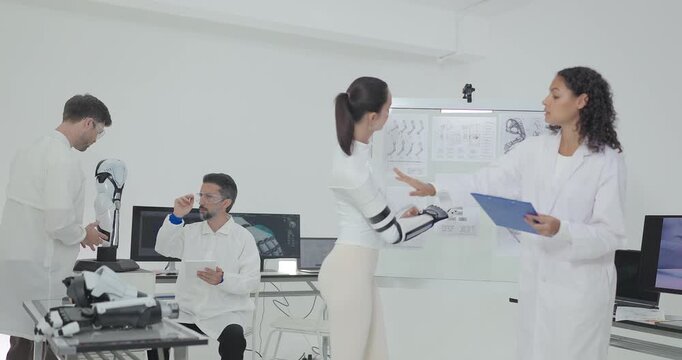 Engineers presenting and testing robotic arm at technical drawing board in white robotics lab