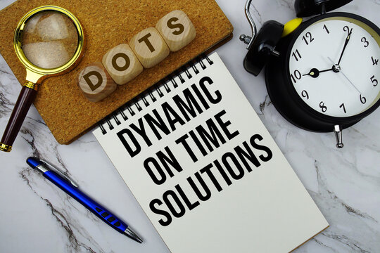 DOTS Dynamic On Time Solutions text written on notepad with calculator and magnifying glass on marble background